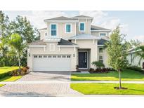 A charming, two-story home with a manicured lawn, brick driveway, and a two-car garage at 1031 Signet, Apollo Beach, FL 33572