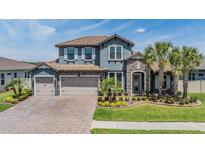 Beautiful two-story home featuring a stone facade, tile roof, three-car garage, and well-manicured landscaping at 29043 Picana Ln, Wesley Chapel, FL 33543