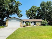 Charming single-story home with stone accents, lush lawn, mature trees and a two car garage at 3565 E Lake Dr, Land O Lakes, FL 34639