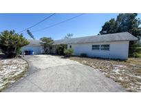 Single story home with white painted facade, long driveway, attached garage, and tidy landscaping at 4719 Alcazar S Way, St Petersburg, FL 33712