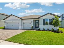 Beautiful single-Gathering home with a well-maintained lawn, a brick driveway, and a three-car garage at 1780 Draughton Dr, Zephyrhills, FL 33541