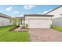 Beautiful one-story home with a two-car garage, manicured lawn, and brick paver driveway at 1847 Brekey Way, Zephyrhills, FL 33541