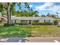 Charming single-story home featuring a well-manicured lawn and mature trees with a lovely front porch at 709 S Himes Ave, Tampa, FL 33609