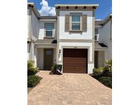 Charming two-story townhome featuring a one-car garage and well-maintained front yard with lovely brick-paved driveway at 18875 Noble Caspian Dr, Lutz, FL 33558