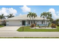 Charming single-story home with well-manicured lawn, white tile roof, and tropical landscaping with palm trees at 260 Coronado Dr, Punta Gorda, FL 33950