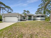 Well-maintained one story home featuring a two-car garage and manicured landscaping at 13210 Essman Ave, Port Charlotte, FL 33953
