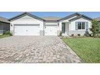 Charming single-Gathering home with brick paved driveway, three-car garage, manicured lawn, and a welcoming entryway at 1799 Draughton Dr, Zephyrhills, FL 33541