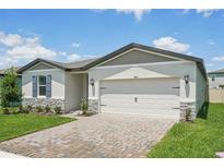 Charming single-story home with a two-car garage, well-manicured lawn, and brick paved driveway at 1859 Draughton Dr, Zephyrhills, FL 33541