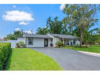 Charming single-story home featuring a well-maintained lawn, dark gray driveway, and thoughtfully designed landscaping at 2110 W Farwell Dr, Tampa, FL 33603