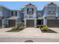 Charming two-story townhome with blue exterior, brown trim, attached garage, and landscaped yard at 6703 Citrus Creek Ln, Tampa, FL 33625