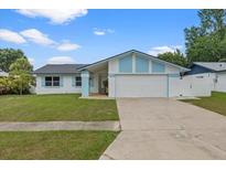 Charming single-story home featuring a two-car garage, well-maintained lawn, and light blue accents at 14506 Sutter Pl, Tampa, FL 33625