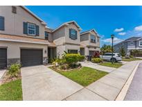 Well-maintained townhomes with garages, blue shutters, and lush landscaping in a manicured community at 8126 Muddy Pines Pl, Tampa, FL 33635