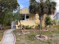 Charming yellow home featuring a well-manicured front yard with lovely palm trees at 1834 28Th N Ave, St Petersburg, FL 33713