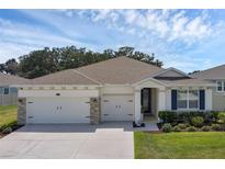 Charming single-story home featuring a two-car garage, stone accents, and professionally landscaped front yard at 10815 Laxer Cay Loop, San Antonio, FL 33576