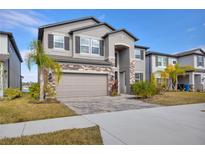 Beautiful two story home featuring a two car garage, stone accents, manicured lawn, and lush palm trees at 3137 Marine Grass Dr, Wimauma, FL 33598