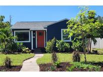 Charming home featuring a blue exterior, complemented by a well-maintained front yard and vibrant landscaping at 420 61St S Ave, St Petersburg, FL 33705
