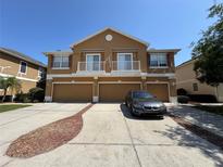 Three-unit townhome with brown exterior, balconies, and three garages at 7544 Red Mill Cir, New Port Richey, FL 34653