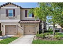 Charming townhome featuring a two-car garage, manicured lawn, and a beautifully landscaped front yard at 11632 Castine St, New Port Richey, FL 34654