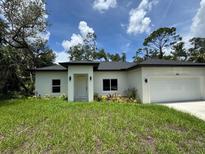 Charming single-story home featuring a well-manicured lawn, white exterior and an attached two-car garage at 353 Warrington Blvd, Port Charlotte, FL 33954