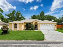 Charming single-story home with manicured lawn, attached two car garage, and bright yellow exterior at 7337 Cone Shell Dr, Spring Hill, FL 34607