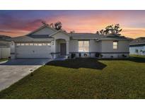Charming single-story home featuring a well-manicured lawn and a two-car garage at sunset at 3118 34Th Avenue E Dr, Bradenton, FL 34208