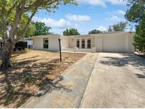 Charming single-story home featuring a driveway and well-maintained front yard under a blue sky at 7604 Tyson Dr, Port Richey, FL 34668