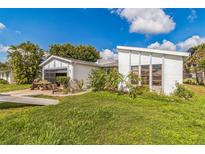 Quaint home featuring white paint, gray trim, and a garage with a screened door at 18430 Alphonse Cir, Port Charlotte, FL 33948