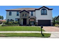 Charming two-story home with a tile roof, stone accents, well-manicured lawn, and a two car garage at 302 Coco Plum Ct, Oldsmar, FL 34677