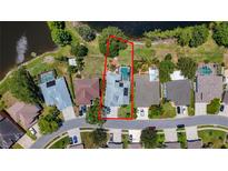 Aerial view of a single Gathering home with a pool and a well-manicured lawn, surrounded by lush greenery and a pond at 1913 Blue River Rd, Holiday, FL 34691