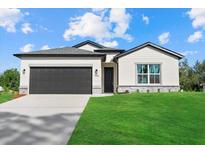 Beautiful new home with a dark garage door and well-manicured lawn under a bright blue cloudy sky at 1486 Ardisia St, North Port, FL 34288