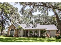 Charming single-story home with stone accents, dormers and a welcoming front porch, surrounded by mature trees and lush landscaping at 2906 Country Breeze Dr, Plant City, FL 33567