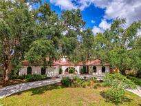 Charming single-story home with a red tile roof, lush landscaping, and a welcoming arched entryway at 2504 Tanglewood Dr, Sarasota, FL 34239