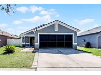 Charming single-story home featuring a well-maintained lawn, grey paint, and a spacious two-car garage at 12829 Kings Lake Dr, Gibsonton, FL 33534