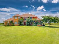Stunning two-story home featuring a clay tile roof, manicured landscaping, and lush green lawn at 37511 Washington Loop Road, Punta Gorda, FL 33982