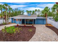 Charming blue single-story home featuring a covered front porch, brick driveway, and well-manicured landscaping at 5108 Saint Albans Ave, Siesta Key, FL 34242