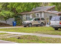 Cozy home exterior with mature trees and vehicles parked in the driveway at 15272 Avalon Ave, Clearwater, FL 33760