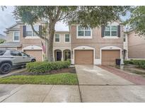 Two-story townhome with brown shutters, a garage, and a well-manicured lawn at 26622 Castleview Way, Wesley Chapel, FL 33544