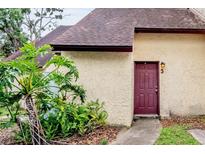 Charming townhome featuring a deep red front door and lush tropical landscaping at 5641 Ashley Oaks Dr # 39, Tampa, FL 33617