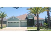 Charming one-story home featuring a three-car garage, manicured lawn, and mature palm trees at 1829 Mira Lago Cir, Ruskin, FL 33570