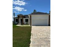 Beautiful new home features lush lawn, brick driveway, and an attached two car garage at 14914 San Domingo Blvd, Port Charlotte, FL 33981
