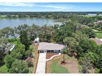 Expansive lakefront property featuring mature trees, lush greenery, and a long driveway leading to a well-maintained home at 14050 Blackjack Rd, Dover, FL 33527