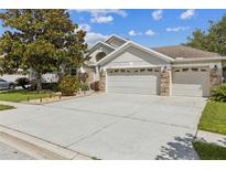 Charming single-story home featuring a three-car garage, stone accents, and well-maintained landscaping at 6935 Runner Oak Dr, Wesley Chapel, FL 33545