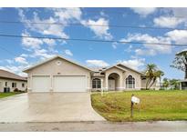 Beautiful single-story home with a two-car garage, lush lawn, and a welcoming arched entryway with decorative windows at 924 Texas St, Englewood, FL 34223