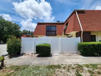 Two-story home with white privacy fence, red tile roof, and green landscaping at 8114 Oak Trace Way # C, Tampa, FL 33634