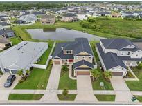 Expansive home features meticulous landscaping, a three-car garage, and a picturesque pond view at 7163 Talamore Dr, Wesley Chapel, FL 33545