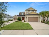 Inviting two-story home boasting a well-manicured lawn, three-car garage, and a striking red front door at 7163 Talamore Dr, Wesley Chapel, FL 33545