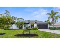 Charming renovated single-story home with a well-manicured lawn, mature landscaping, and a two-car garage at 2421 Valkaria Ave, North Port, FL 34286