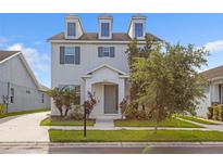 Two-story home featuring a charming front entrance, manicured lawn, and dormer windows at 5254 Suncatcher Dr, Wesley Chapel, FL 33545