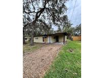 A quaint single-story home featuring a gravel driveway and mature trees in a natural setting at 5026 Osprey Ln, New Port Richey, FL 34652