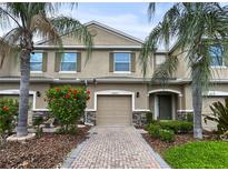 Inviting townhome with a well manicured front yard, brick driveway, and lush tropical landscaping at 26835 Juniper Bay Dr, Wesley Chapel, FL 33544
